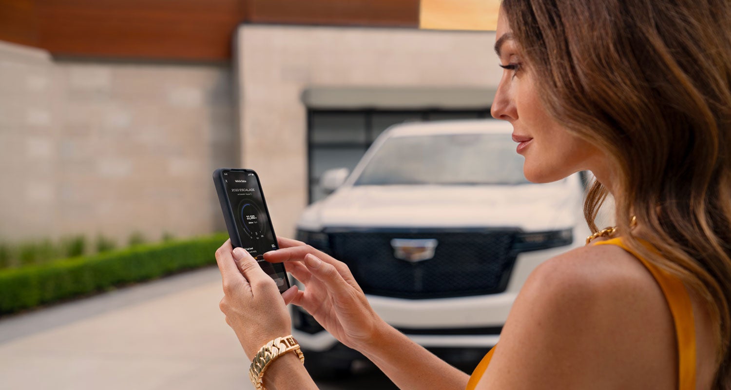 lady checking her mobile with a Cadillac vehicle background | Tom Peacock Cadillac in HOUSTON TX